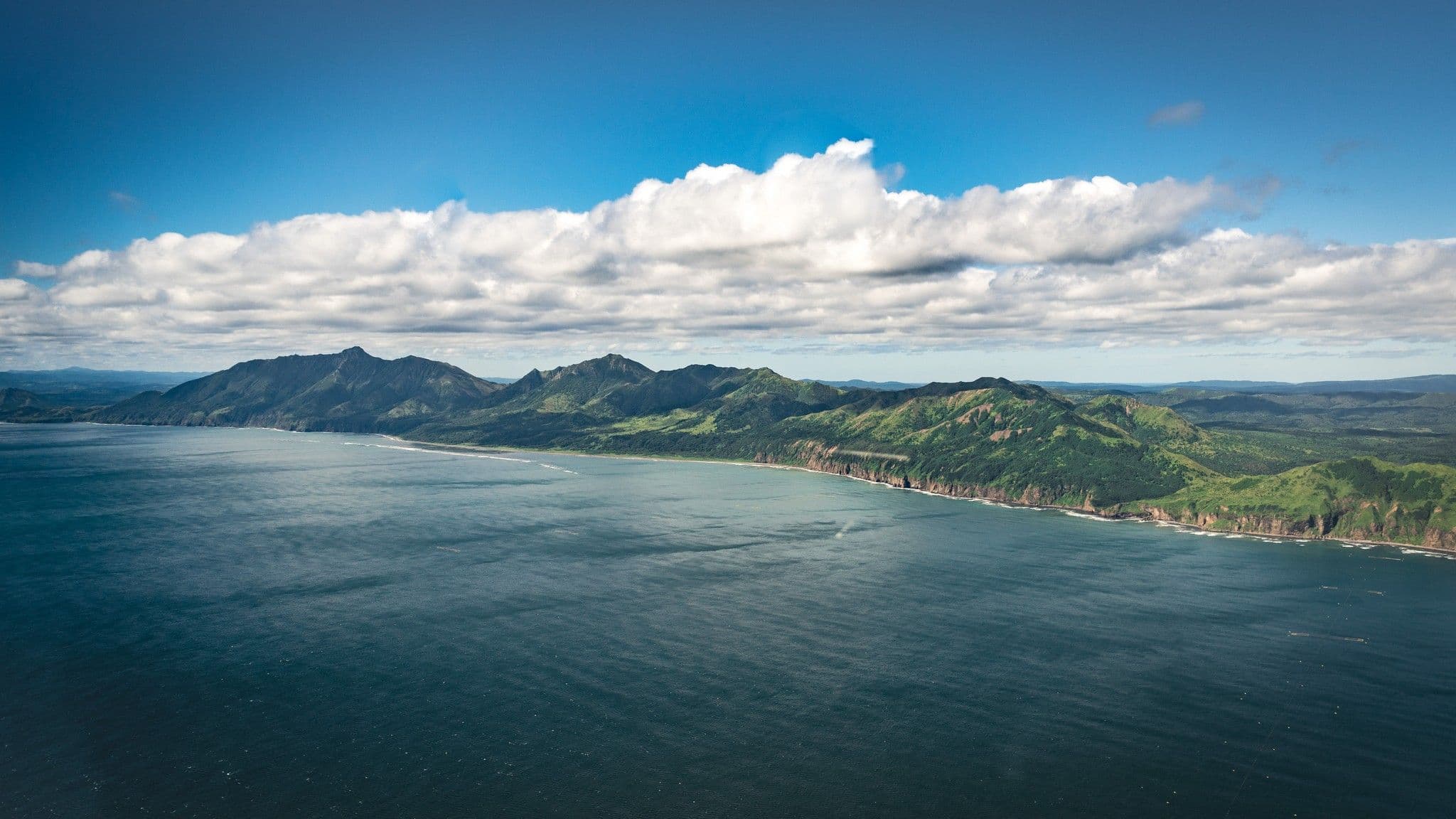 Вид на остров Сахалин с высоты, с синим океаном и зелеными лесами